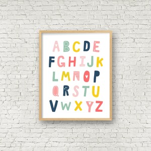 May include: A framed alphabet print with colorful letters in pink, blue, yellow, and green. The letters are stylized and have different patterns and designs. The background is white.