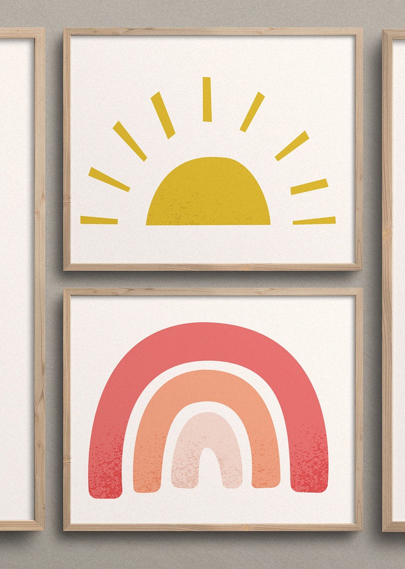 May include: Two framed prints with a minimalist design. The top print features a yellow sun with rays, while the bottom print features a pink, orange, and peach rainbow.