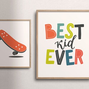 K&ouml;nnte beinhalten: Zwei gerahmte Drucke, einer mit einem roten Skateboard und der andere mit dem Text "BEST kid EVER" in bunten Buchstaben.