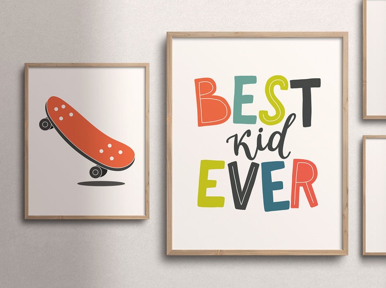 K&ouml;nnte beinhalten: Zwei gerahmte Drucke, einer mit einem roten Skateboard und der andere mit dem Text "BEST kid EVER" in bunten Buchstaben.