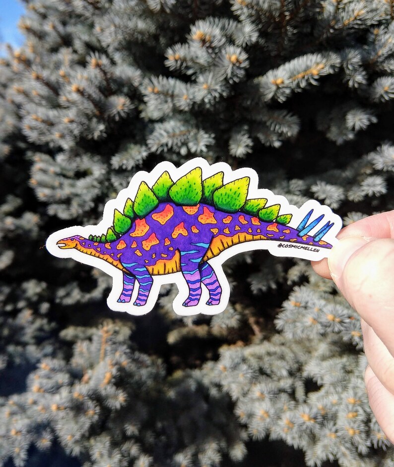May include: A colorful sticker of a dinosaur with green spikes, purple and orange spots, and blue stripes. The dinosaur is standing on a white background. The sticker has the text "@cosmicmellen" on the bottom right corner.