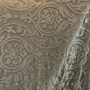 Könnte beinhalten: Schwarzer Stoff mit einem erhabenen, geprägten Damastmuster. Das Muster ist ein sich wiederholendes Design aus Wirbeln und Blättern.