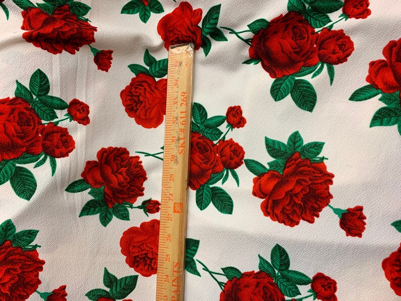 White 4 way stretch poly liverpool fabric with red all over roses green leaves design sold by the yard