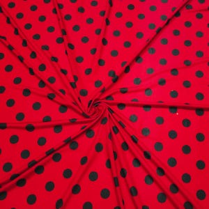 May include: Red fabric with a black polka dot pattern. The fabric is folded and twisted, showing the pattern from different angles.