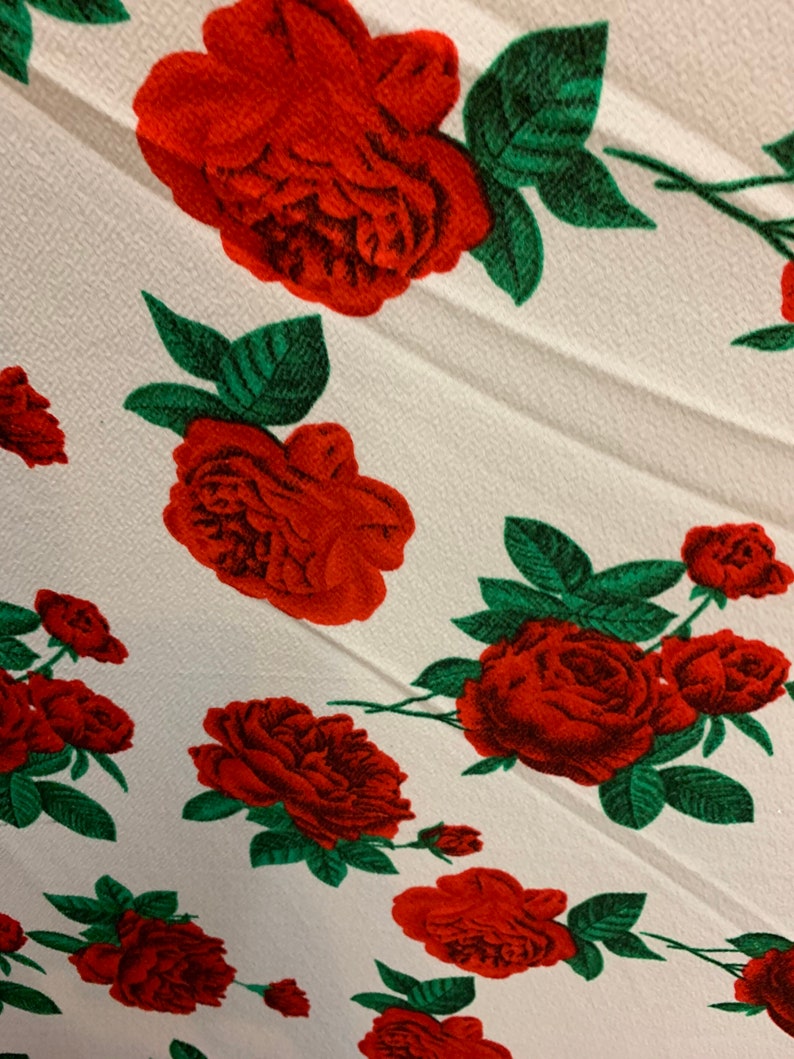 White 4 way stretch poly liverpool fabric with red all over roses green leaves design sold by the yard