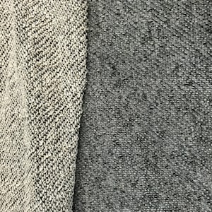 May include: Close-up of two fabric swatches. One swatch is a light gray and white knit with a textured appearance. The other is a darker gray, also with a textured appearance. The fabrics are side by side, showcasing the contrast in color and texture.