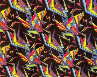 May include: A black fabric with a repeating pattern of colorful geometric shapes, including lightning bolts, triangles, and squares. The colors include yellow, blue, green, pink, and purple.