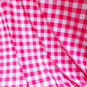 Könnte beinhalten: Rosa-weißes Gingham-Gewebe mit einer diagonalen Falte. Der Stoff hat ein kariertes Muster.