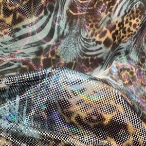 Peut inclure: Gros plan sur un tissu avec un mélange d'imprimés animaliers. Le tissu présente un imprimé léopard, des rayures zébrées et un motif scintillant à pois. Les couleurs incluent le marron, le noir et des reflets irisés.