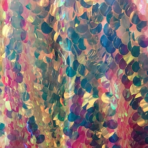 May include: Close-up of iridescent fabric with overlapping, round sequins in shades of pink, green, and blue.