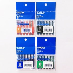 K&ouml;nnte beinhalten: Vier Packungen Brother Stamp Creator Pro Nachf&uuml;lltintenpatronen. Die Packungen sind blau und wei&szlig; und jede enth&auml;lt eine Tintenpatrone in einer anderen Farbe: rot, schwarz, blau und gr&uuml;n. Die Packungen enthalten auch den japanischen Text "補充用インクカートリッジ", der mit "Nachf&uuml;lltintenpatrone" &uuml;bersetzt wird.