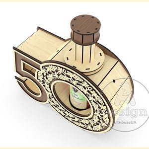 May include: Wooden wine bottle holder shaped like the number 50, with a decorative floral design and a small wooden top. The holder is designed to hold a bottle of wine.