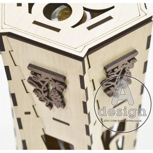 May include: A wooden box with a hexagonal shape and a decorative design. The box is made of light wood and has a dark brown trim. The box has a small opening on the top and a decorative design on the side. The box is labeled "A design" and "etsy.com/shop/ArtHouseUA".