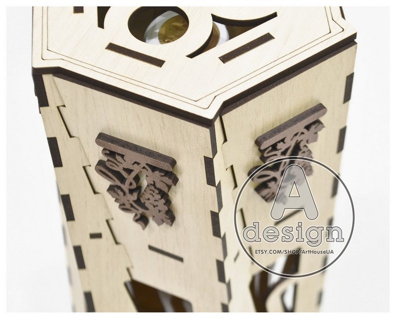 May include: A wooden box with a hexagonal shape and a decorative design. The box is made of light wood and has a dark brown trim. The box has a small opening on the top and a decorative design on the side. The box is labeled "A design" and "etsy.com/shop/ArtHouseUA".