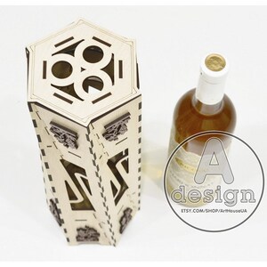 May include: A wooden wine bottle holder with a hexagonal top and intricate cutouts. The holder is made of light brown wood and has a dark brown stain. The holder is designed to hold a standard-sized wine bottle.