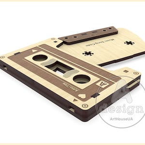 May include: A wooden cassette tape with a brown and beige color scheme. The cassette is open and the tape is visible. The text "Artist/Time" and "Music Song Code" are printed on the cassette.