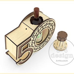 May include: Wooden wine bottle holder shaped like the number 50. The holder is made of light brown wood and has a decorative design around the bottle opening. The holder is designed to hold a standard-sized wine bottle.