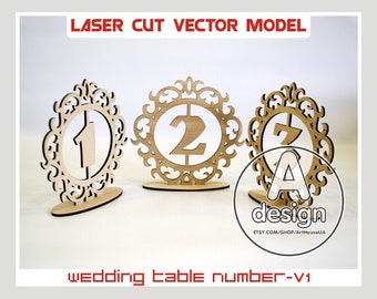 May include: Three laser cut wooden table numbers with ornate frames. The numbers are 1, 2, and 7. The numbers are designed for a wedding.