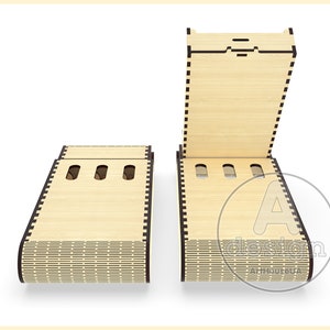 May include: A wooden box with a hinged lid and three slots. The box is made of light wood with a dark brown border. The box is open and the lid is propped up.