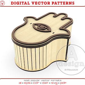 May include: A wooden box shaped like a hamsa hand with a carved eye in the centre. The box has a wood grain pattern and is a light brown colour.