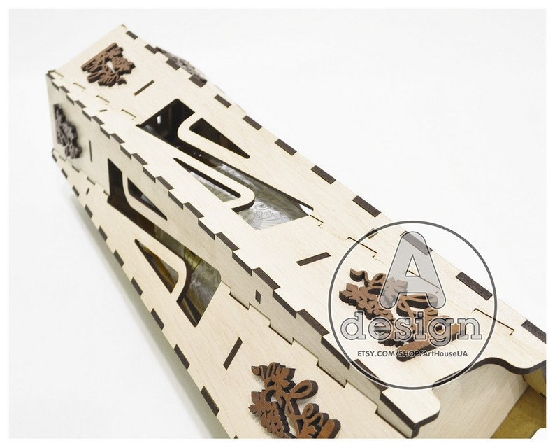 May include: A wooden bottle holder with a cutout design, featuring intricate floral details. The holder is made of light-colored wood and has a natural finish.