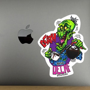 Può includere: Un personaggio zombie verde con un viso di teschio versa il caffè da una caraffa in una tazza. Il testo recita "Death Before Decaf" con l'account Instagram "@staywokecakes" sotto.