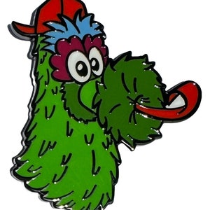 Könnte beinhalten: Grünes, flauschiges Monster mit einem roten Hut und einer langen roten Zunge, die herausragt. Das Monster hat große Augen und eine rosafarbene Nase.