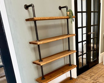 May include: A five-tier industrial style shelf unit with black metal pipes and wooden shelves. The shelves are made of reclaimed wood and have a natural finish. The shelf unit is mounted to a wall and is in a hallway with a wooden floor.