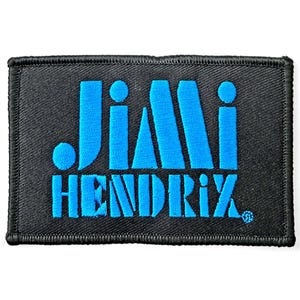 May include: A rectangular black patch with the name "JIMI HENDRIX" embroidered in bright blue. The text is in a stylized font, with the name arranged in two lines. The patch has a black border.