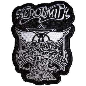 Pode incluir: Patch bordado em preto e branco com o nome da banda "Aerosmith" em uma fonte estilizada. O patch inclui o texto "Permanent Vacation 1987" e um gráfico de um emblema alado e uma criatura rosnando.