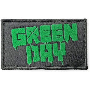 Puede incluir: Parche bordado con el logotipo de la banda Green Day sobre un fondo de tela negro. El logotipo es verde y presenta el nombre de la banda en una fuente estilizada.