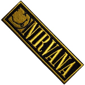 May include: Embroidered patch with the word "NIRVANA" in gold lettering on a black rectangular background. The top left corner has a gold smiley face with an "X" for eyes and a tongue sticking out.
