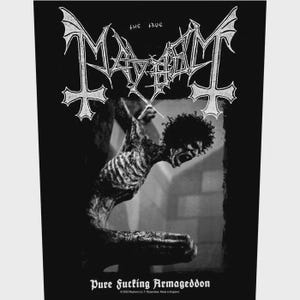 May include: A black and white rectangular patch featuring the text "The True Mayhem" in a stylized font at the top. Below, a monochromatic image depicts a skeletal figure. The text "Pure Fucking Armageddon" is printed at the bottom of the patch.