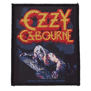 Puede incluir: Parche cuadrado negro con el texto "OZZY OSBOURNE" en amarillo y rojo. El parche incluye una ilustración de una figura parecida a un zombi. El fondo es azul oscuro y negro.