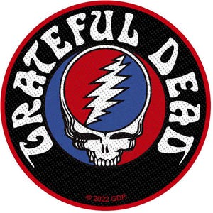 May include: Circular patch with the words "Grateful Dead" in white, arched around a central design. The design features a skull with a lightning bolt, set against a red and blue background. The patch has a black background and a red border. The copyright date is 2022.