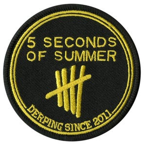 May include: A circular black embroidered patch with yellow detailing. The text reads "5 SECONDS OF SUMMER" and "DERPING SINCE 2011." A yellow stylized design is in the centre.
