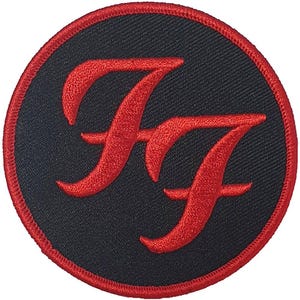 May include: Circular black patch with a red embroidered double "F" logo, framed by a red border. This patch is designed for application on clothing or accessories, showcasing a striking, well-known emblem.