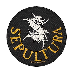 Könnte beinhalten: Ein runder, schwarzer Aufnäher mit dem Wort "SEPULTURA" in Gold, das sich oben und unten wölbt. Ein weißes, abstraktes Design befindet sich in der Mitte. Der Text "©2010 SEPULTURA" steht unten.