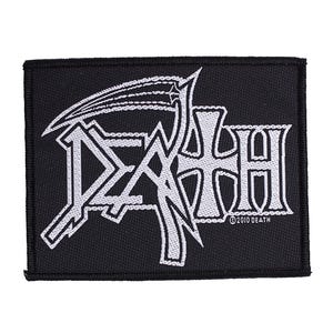 Puede incluir: Parche rectangular negro con el logo DEATH blanco y una guadaña. El texto "©2010 DEATH" está debajo del logo. El parche es probablemente para una chaqueta o bolso, y es merchandising musical.