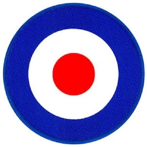 May include: Circular patch featuring a bullseye design. The patch has a blue outer ring, a white inner ring, and a red center circle. The patch is likely an embroidered or fabric applique.