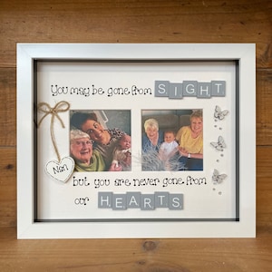 May include: A white picture frame with two photos of a family. The frame has a grey background with the words "You may be gone from SIGHT. but you are never gone from our HEARTS." written in black letters. The words are made up of letter tiles. There is a small wooden heart with the word "Nan" written on it.