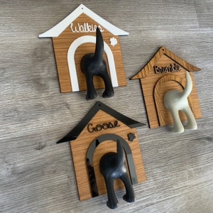 May include: Three wooden dog house shaped hooks with black and white dog silhouettes. The hooks are labeled "Walkies", "Bramble", and "Goose".