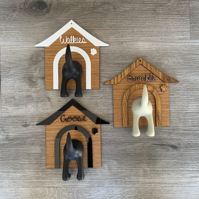 May include: Three wooden dog house shaped coat hooks with black and white dog silhouettes. The hooks are labeled "Walkies", "Bramble", and "Goose".