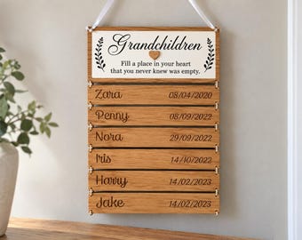 May include: A hanging wooden sign with a white top panel featuring the text Grandchildren Fill a place in your heart that you never knew was empty. Below are six horizontal oak slats, each engraved with a name and a date in MM/DD/YYYY format.