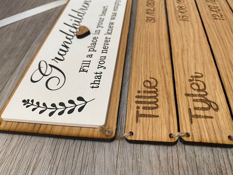 May include: Wooden sign with the text "Grandchildren Fill a place in your heart that you never knew was empty" and three smaller wooden signs with the names "Tillie", "Tyler" and the dates "31/12/20", "15/08/20", "12/07/20".