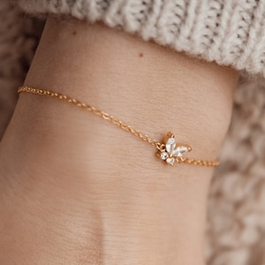 Peut inclure: Un bracelet délicat en chaîne dorée avec un petit charme papillon scintillant.