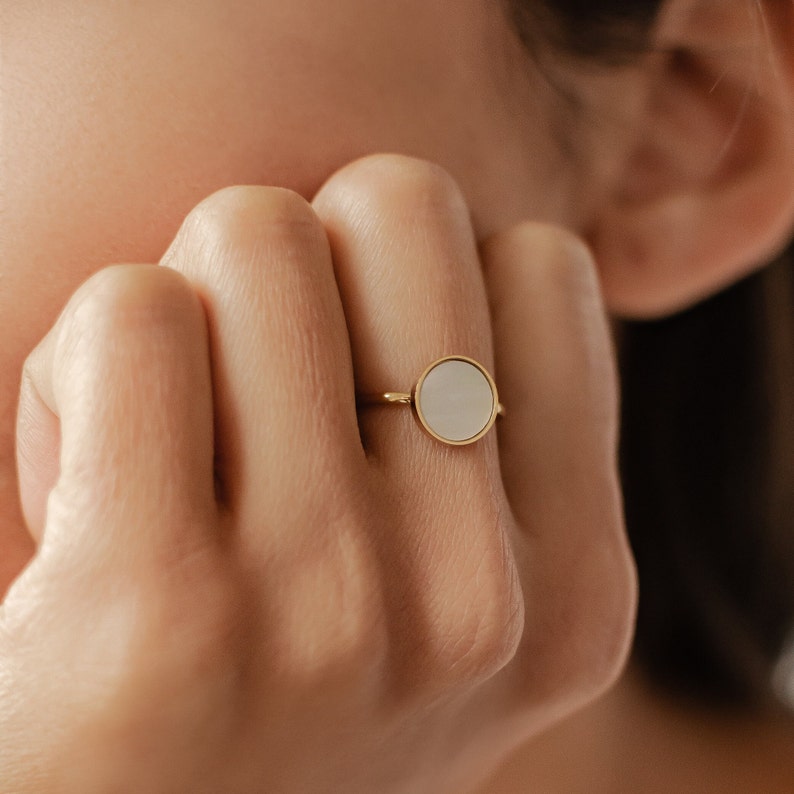K&ouml;nnte beinhalten: Ein goldener Ring mit einem wei&szlig;en runden Stein in der Mitte.