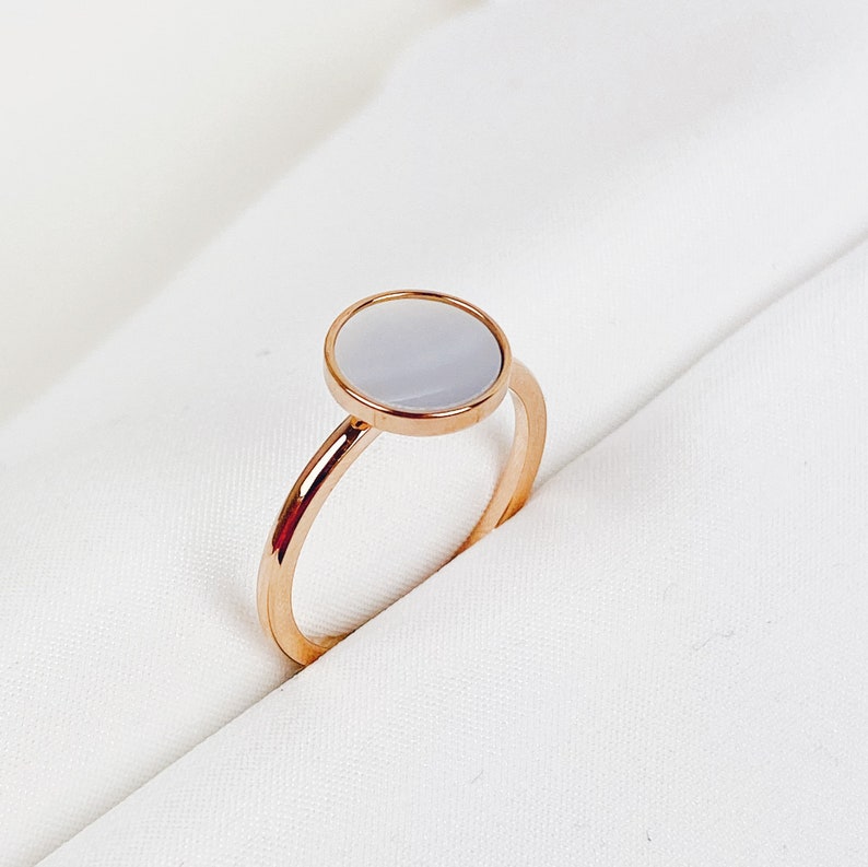 K&ouml;nnte beinhalten: Ein Ring aus Ros&eacute;gold mit einem wei&szlig;en, runden Perlmuttstein.
