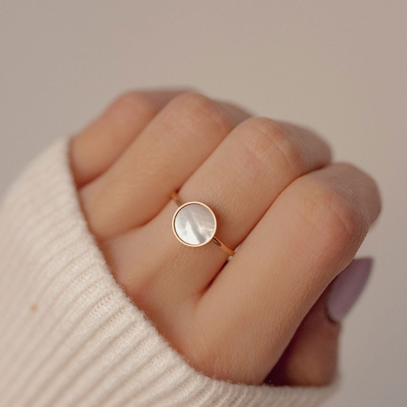 K&ouml;nnte beinhalten: Ein goldener Ring mit einem wei&szlig;en Perlmuttstein.