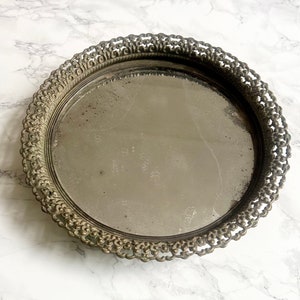 Peut inclure: Un plateau argenté avec un bord décoratif, orné et festonné. Le plateau a une surface miroir.